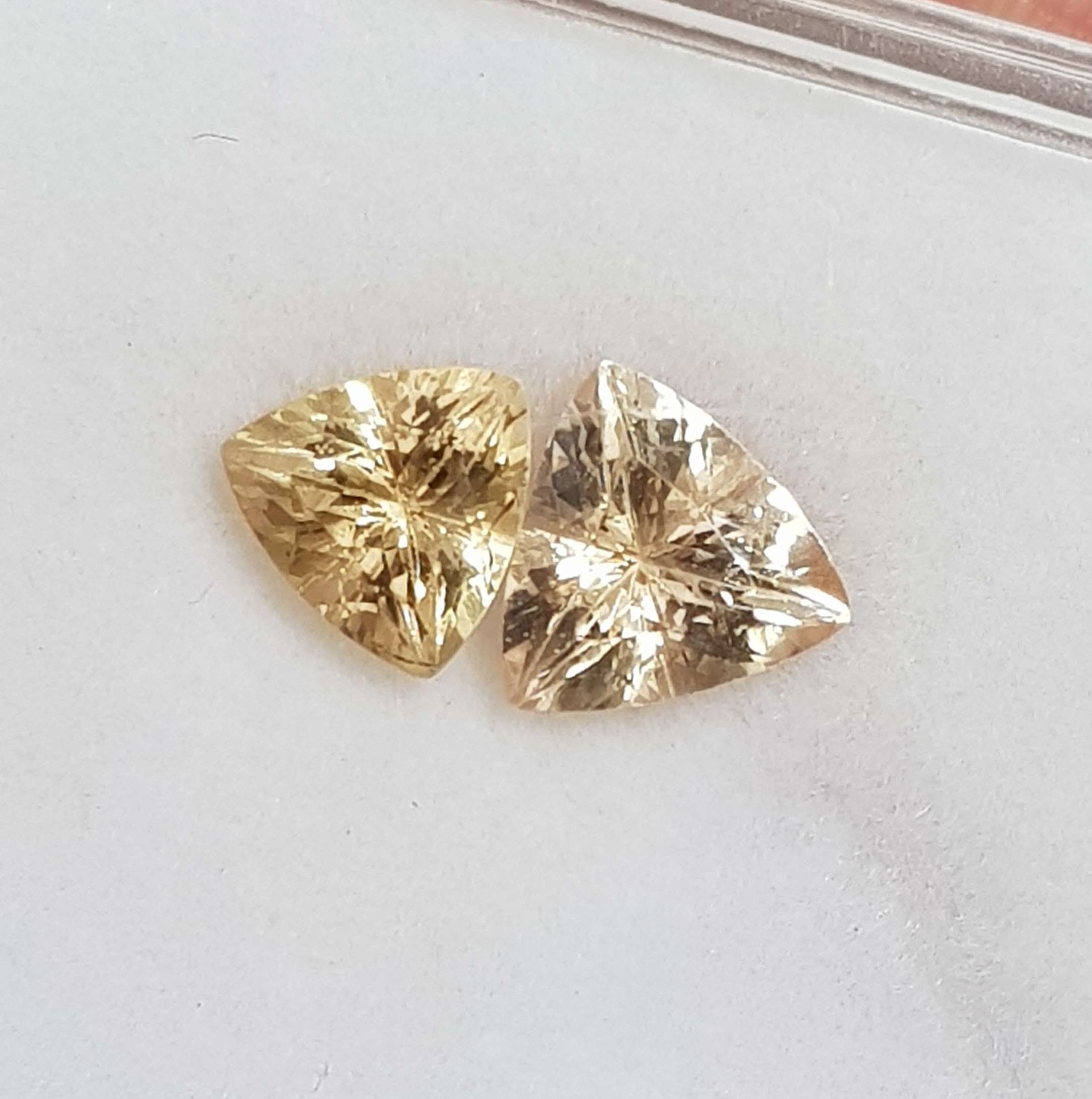 זוג אבנים חן צהבהבות בחיתוך טריליון עם ברק וניצוצות על רקע בהיר